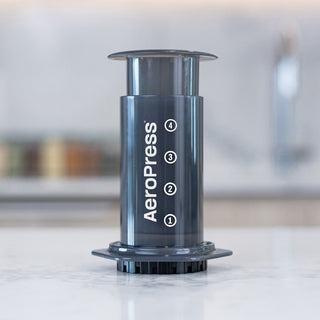 AeroPress Original Coffee Maker in black polypropylene with clear measurement markings on a kitchen counter