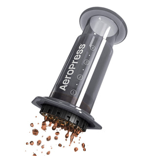 AeroPress Original Coffee Maker brewing coffee with dark grounds falling from black filter cap