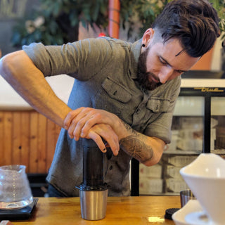 Man using AeroPress Original Coffee Maker with black polymer pressing coffee over metal cup