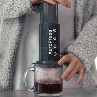 AeroPress Original Coffee Maker brewing fresh coffee over a clear glass mug with visible steam