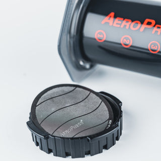 AeroPress Stainless Steel Reusable Filter with fine mesh and black plastic holder on white background