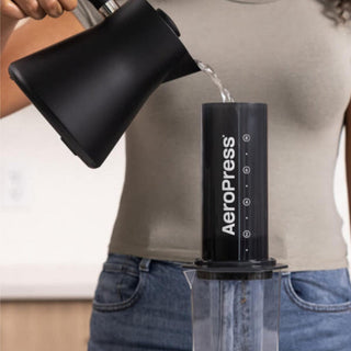 AeroPress XL Coffee Press in black with water being poured from a matte black kettle
