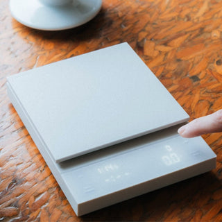 HARIO Polaris Coffee Scale in matte silver with digital display being activated by a finger tap