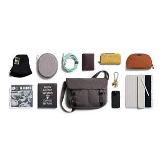 Bellroy Cinch Messenger Bag in charcoal displayed with daily essentials on white background