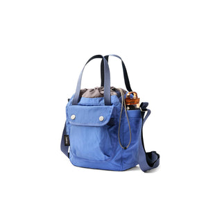 Bellroy Cinch Bucket Bag in blue recycled nylon with front pocket and adjustable strap visible