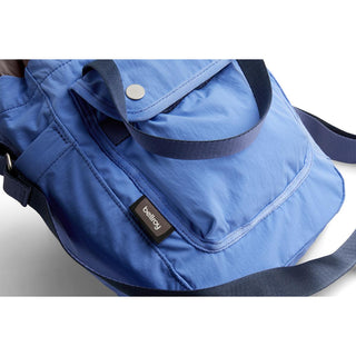 Bellroy Cinch Bucket Bag in blue recycled nylon with front pocket and adjustable strap close-up view