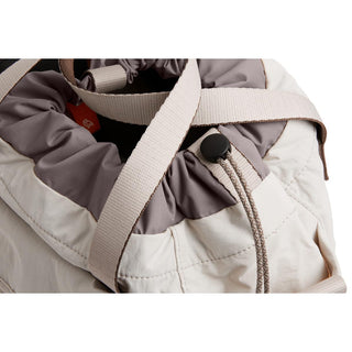 Bellroy Cinch Bucket Bag close-up showing cream fabric with gray drawstring closure and beige strap