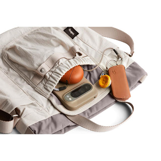 Bellroy Cinch Bucket Bag in beige with drawstring closure and visible everyday carry items inside