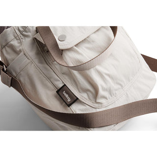 Bellroy Cinch Bucket Bag in light fabric with adjustable brown strap and front flap pocket detail