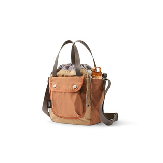 Bellroy Cinch Bucket Bag in tan recycled nylon with front pocket and adjustable strap angled view
