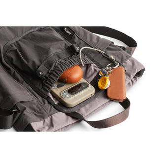 Bellroy Cinch Bucket Bag in gray with front pocket holding keychain, gadget, and small accessories