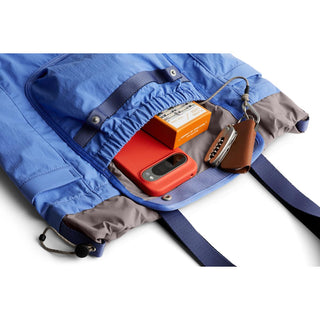 Bellroy Cinch Tote in blue recycled fabric showing open top with phone, keys, and small box inside