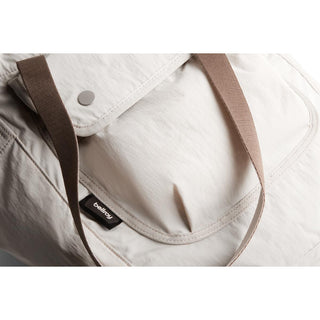Bellroy Cinch Tote in light fabric with brown straps and front flap pocket detail close-up view