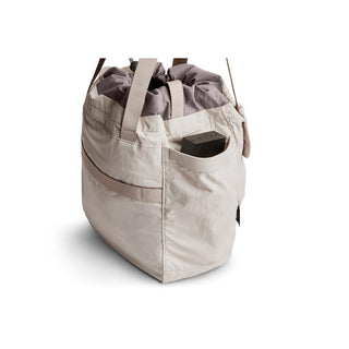 Bellroy Cinch Tote in light beige with external pocket and drawstring closure made from recycled nylon fabrics