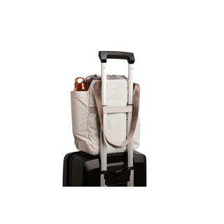 Bellroy Cinch Tote in light fabric secured to suitcase handle with side pocket holding copper bottle