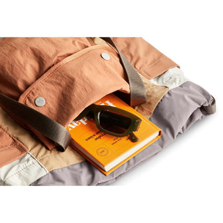Bellroy Cinch Tote open showing orange book and black sunglasses inside nylon fabric bag