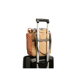Bellroy Cinch Tote secured on suitcase handle showing recycled fabric and side pocket with bottle slot