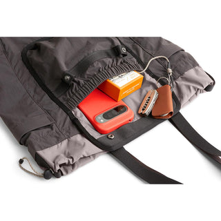 Bellroy Cinch Tote in gray recycled nylon with front pocket holding gadgets and accessories