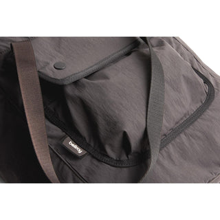 Bellroy Cinch Tote in black recycled nylon with flap pocket and dual colored straps close-up view
