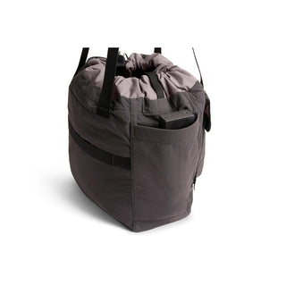 Bellroy Cinch Tote in dark recycled nylon with drawstring top and exterior side pocket carrying a device