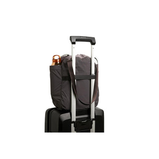 Bellroy Cinch Tote in dark fabric secured on suitcase handle with visible water bottle pocket