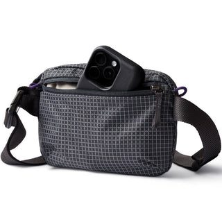 Bellroy Lite Belt Bag in textured recycled fabric with front zip pocket holding a smartphone