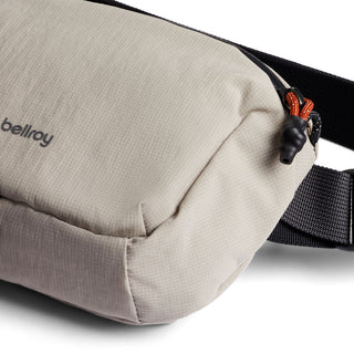 Bellroy Lite Belt Bag in beige recycled fabric with black strap and zipper pull detail