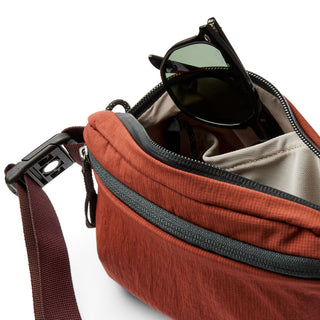 Bellroy Lite Belt Bag in rust color showing interior pocket and black sunglasses inside