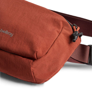 Bellroy Lite Belt Bag in rust red with textured recycled nylon fabric and adjustable strap detail