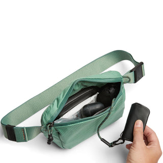Bellroy Lite Belt Bag in soft green recycled nylon with zipper and adjustable strap showing contents