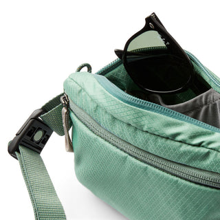 Bellroy Lite Belt Bag in green recycled nylon with open compartment and sunglasses inside