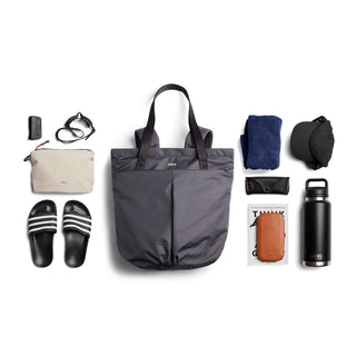 Bellroy Lite Totepack in checkered fabric with everyday essentials arranged on white background