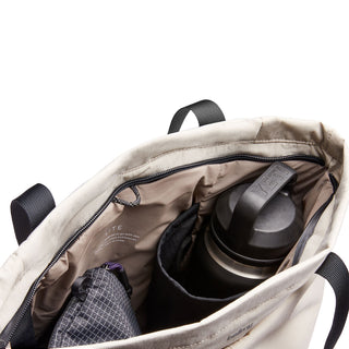 Bellroy Lite Totepack in beige with organized interior pockets holding a water bottle and pouch