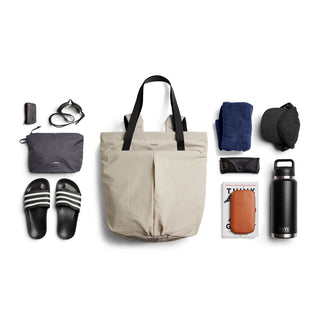 Bellroy Lite Totepack in beige with black handles, styled with daily essentials neatly arranged around it