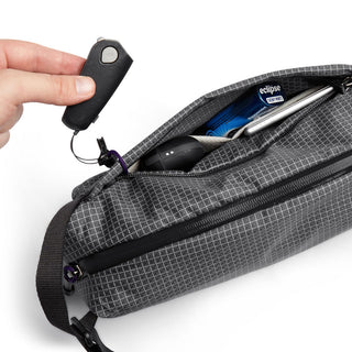 Bellroy Lite Sling in gray with grid pattern shows key fob attachment and organized interior pockets
