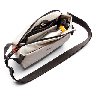 Bellroy Lite Sling Mini in light beige showing multiple compartments with travel essentials inside
