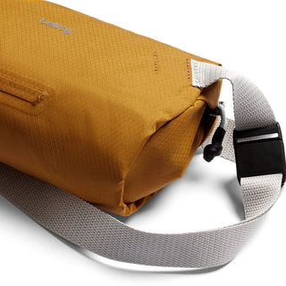 Bellroy Lite Sling Mini in mustard yellow with textured fabric and adjustable light gray strap close-up detail