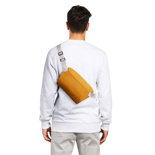 Bellroy Lite Sling Mini worn crossbody in mustard color, showing compact size and adjustable strap