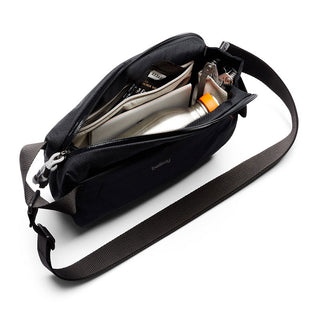 Bellroy Lite Sling Mini crossbody bag open showing organized compartments and strap detail in black fabric