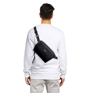 Black Bellroy Lite Sling Mini worn crossbody on a person’s back with adjustable strap visible