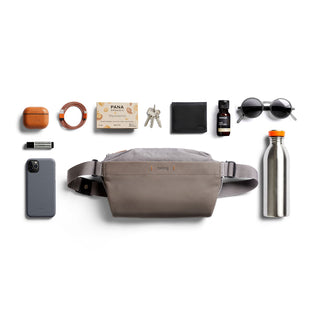Bellroy Sling Mini Premium - 7L in taupe premium leather and water-resistant fabric flat lay with accessories