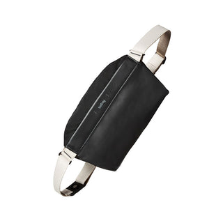 Bellroy Sling Mini Premium - 7L black leather crossbody bag with cream adjustable strap angle view