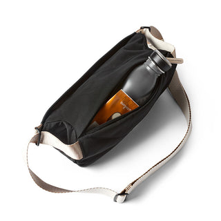 Bellroy Sling Mini Premium - 7L black crossbody bag with main compartment holding water bottle and wallet
