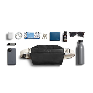 Bellroy Sling Mini Premium - 7L black leather sling bag styled with daily essentials on white background