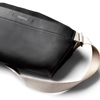 Bellroy Sling Mini Premium - 7L black leather crossbody bag with beige adjustable strap close-up