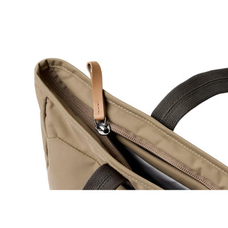 Bellroy Tokyo Tote Compact in tan woven fabric with leather zipper pull and black handles close-up view