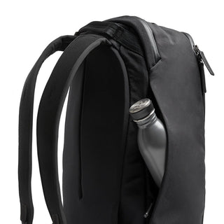 Bellroy Transit Workpack 20L in black with padded straps and side pocket holding a silver water bottle