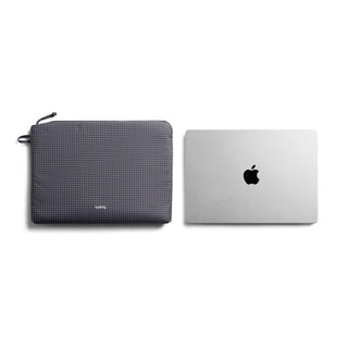 Bellroy Lite Laptop Sleeve 14 in dark grey recycled fabric next to closed silver laptop