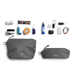 Bellroy Lite Pouch Duo in recycled nylon with grid texture, shown alongside travel and personal care items
