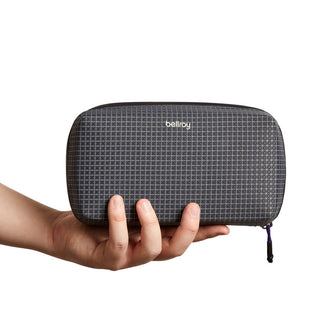 Bellroy Tech Kit black fabric case with grid pattern held in hand for size reference